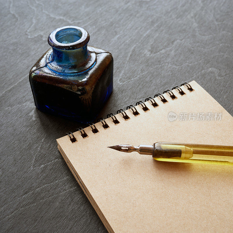 旧钢笔，笔记本和墨水瓶在黑色的背景