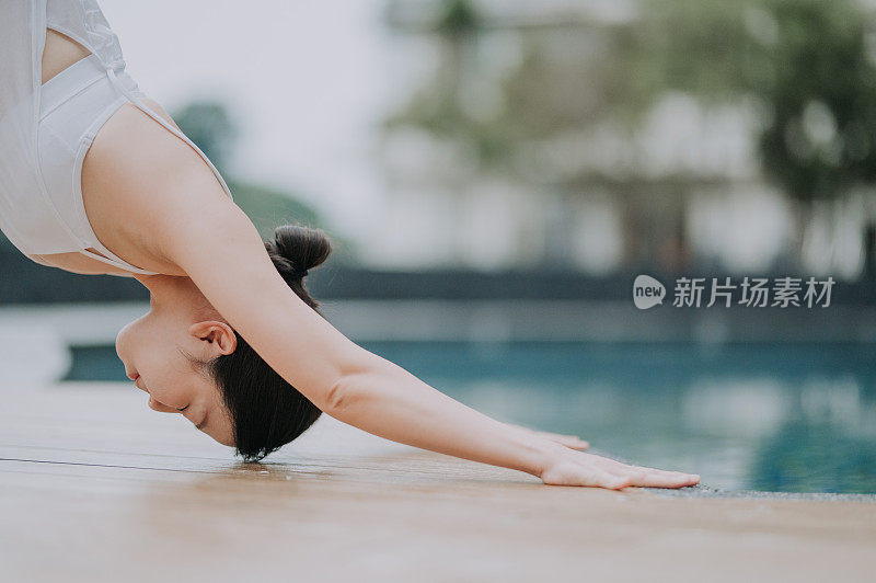 一位亚洲华裔女瑜伽教练示范下犬式