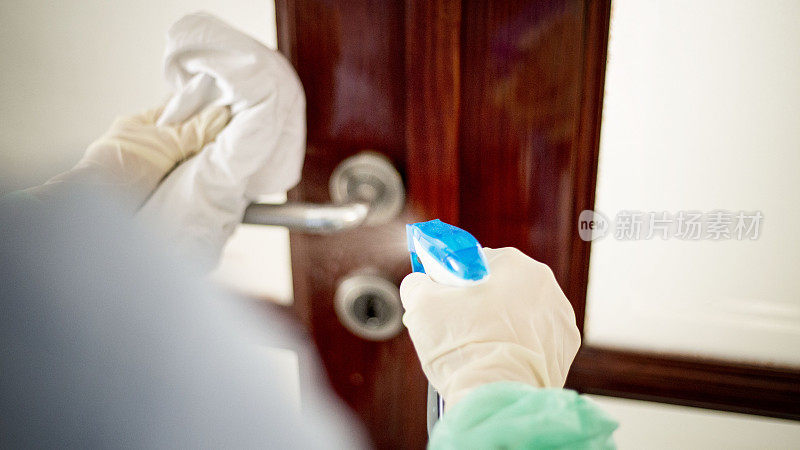 年轻女子正在清洁和消毒门把手