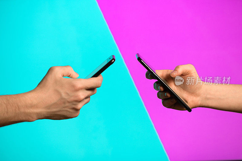 一名男性和女性手拿手机相对，背景分为粉色和蓝色两半