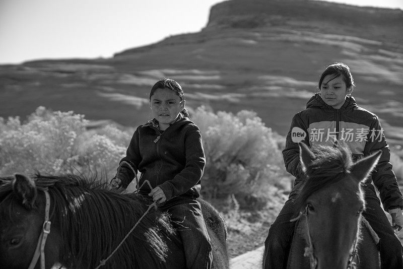 年轻的纳瓦霍兄弟姐妹骑着马的黑白静止摄影