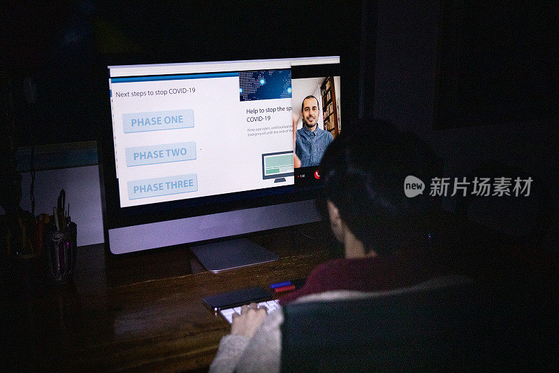 封锁期间在夜间工作妇女阅读新冠肺炎新闻并召开视频会议