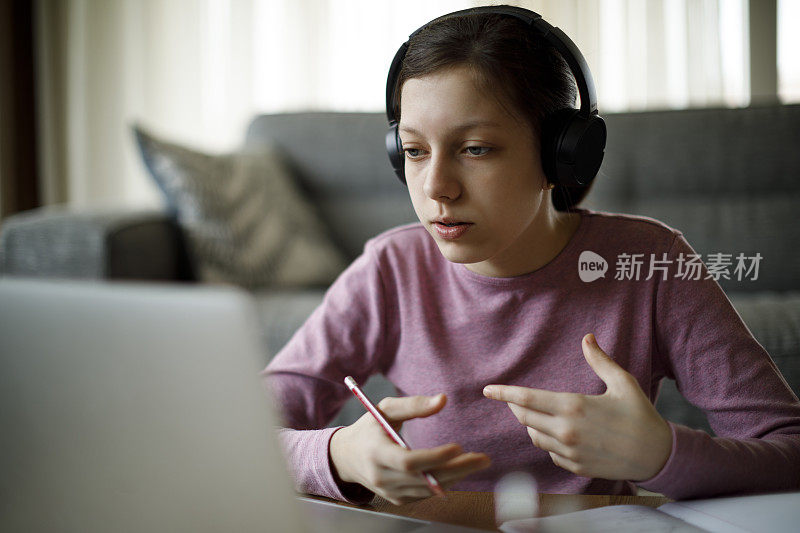 十几岁的女孩戴着耳机在家上在线学校