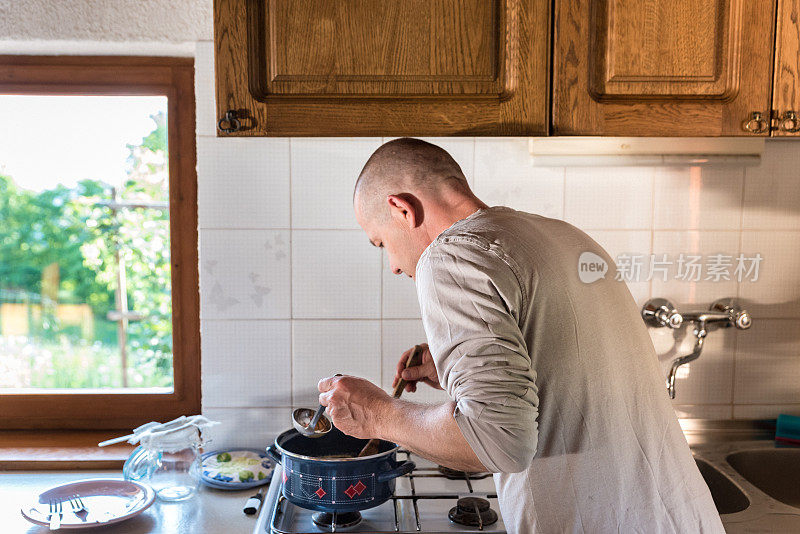家庭厨房里的男人正在等待完美的融化黄油来制作酥油