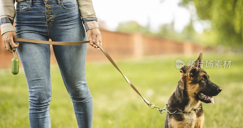 一个年轻女子和她的德国牧羊犬在公园散步