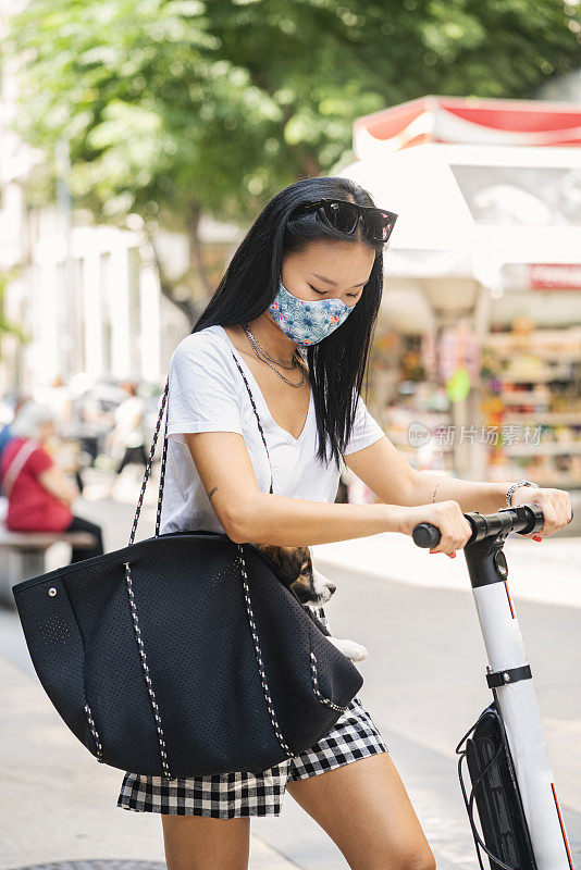 年轻女子戴着防护面罩，骑着电动车在城市中穿行