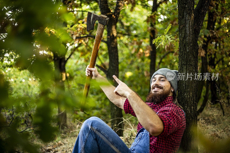 年轻人在砍柴时休息伐木工人森林里的一个伐木工人每天都在准备和砍柴