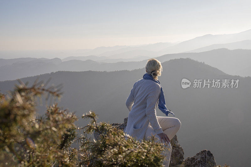 清晨，女徒步旅行者在阳光明媚的山脊上放松