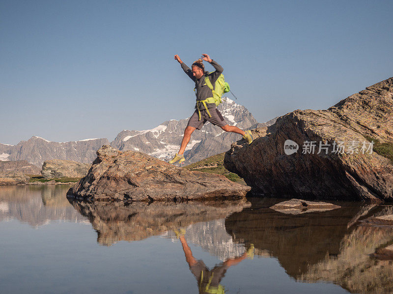 一个人在高山湖上从一块岩石跳到另一块岩石上