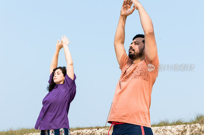 一对成年夫妇在沙滩上打太极拳