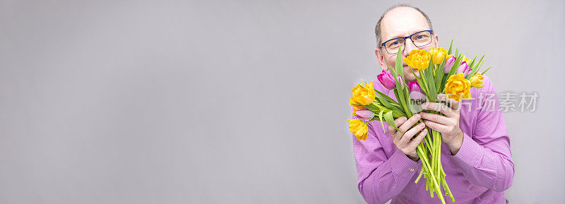 一个白种人，送了一束明媚的春天的花，一束郁金香。一大束黄色和紫色的郁金香。