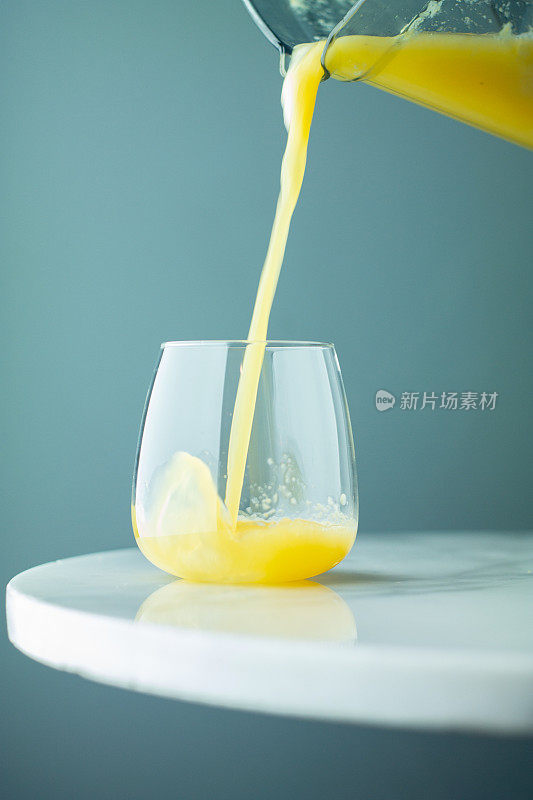 一杯新鲜橙汁，泡沫从壶中涌出