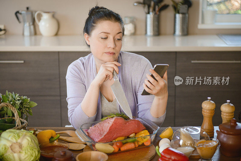 女人在厨房做饭(牛肉和智能手机)