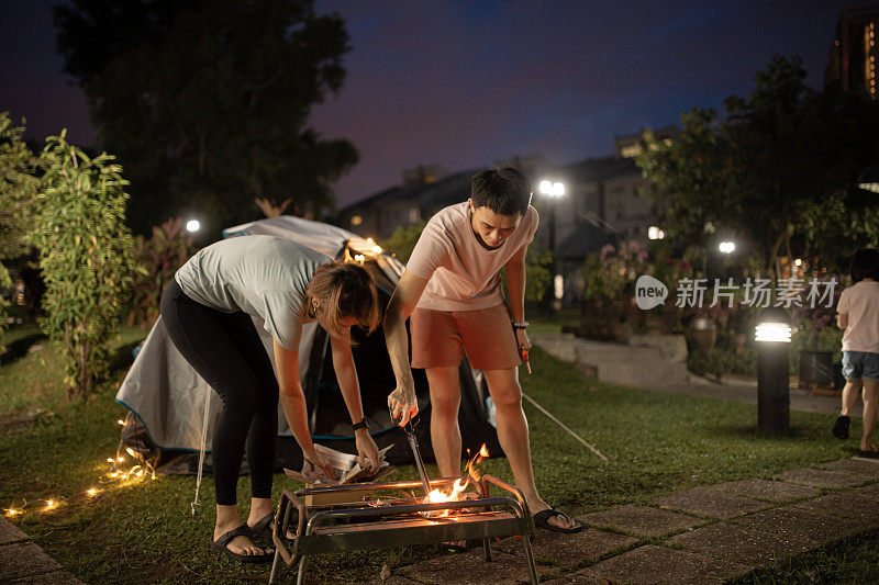 亚裔华人父母在自家后院搭起营火，进行周末度假活动