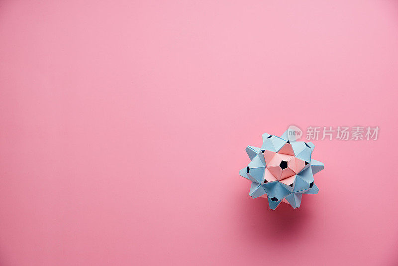 MulticolorÂ手工制作modularÂ折纸球或Kusudama孤立在粉红色的背景。视觉艺术，几何学，折纸艺术，纸工艺品。俯视图，特写，选择性聚焦，复制空间。