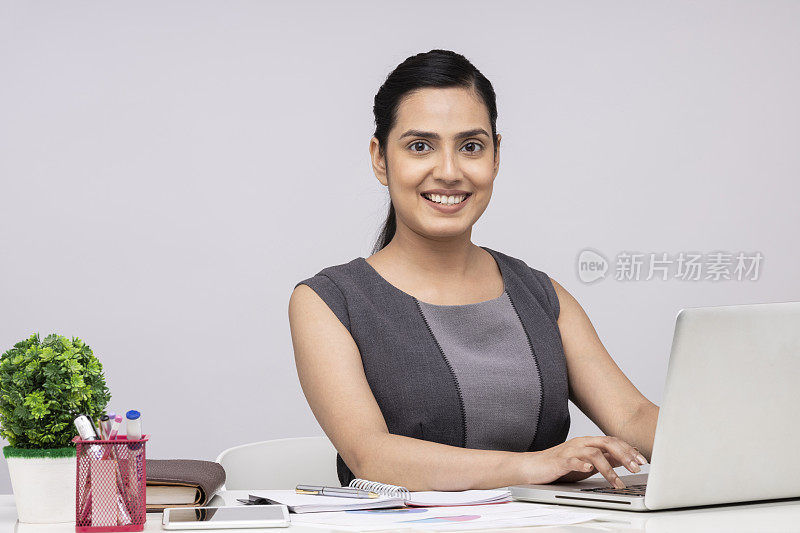 一个有吸引力的年轻商业女性的肖像使用笔记本电脑坐在孤立的白色背景
