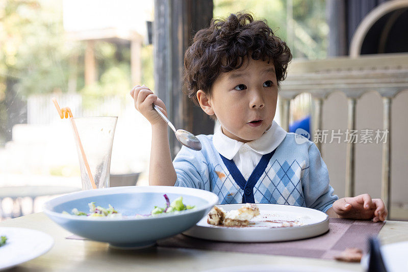 一个小男孩在餐馆里吃沙拉