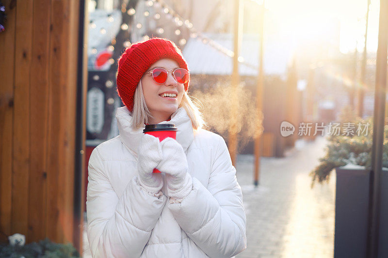 戴太阳镜的妇女在露天咖啡馆用杯子喝咖啡