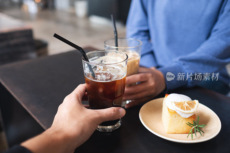 咖啡桌上一对夫妇用柠檬蛋糕碰咖啡杯的特写