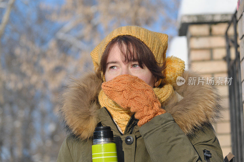 一个女人正在冬天的街道上喝茶