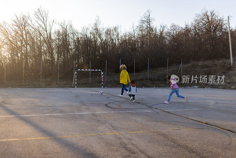 妈妈和孩子们在运动场上踢足球