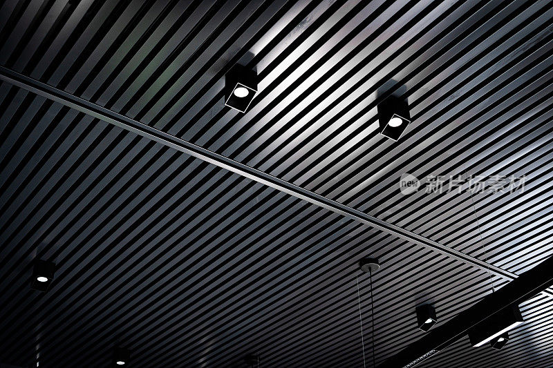 带射灯的板条天花板的底部视图。抽象现代建筑或室内背景采用黑白几何结构。