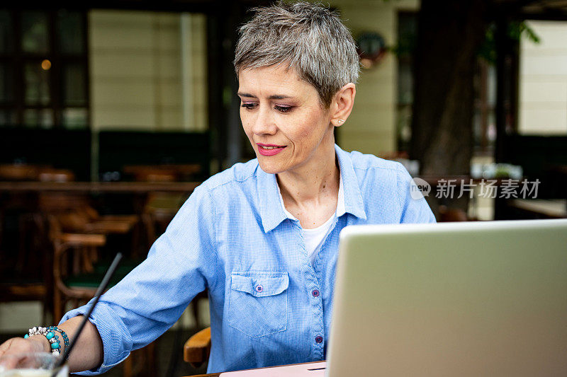成熟的短发女商人在笔记本电脑上工作