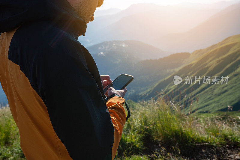 徒步旅行者在日落时分在山上使用智能手机