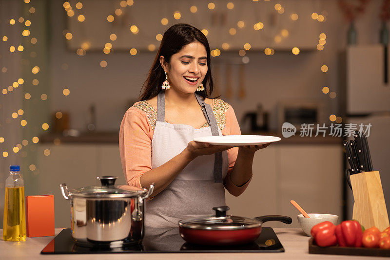 一个年轻女子的肖像烹饪食物在厨房的股票照片