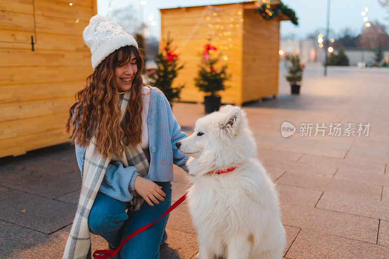 美丽的年轻女孩在户外玩她的萨摩耶狗