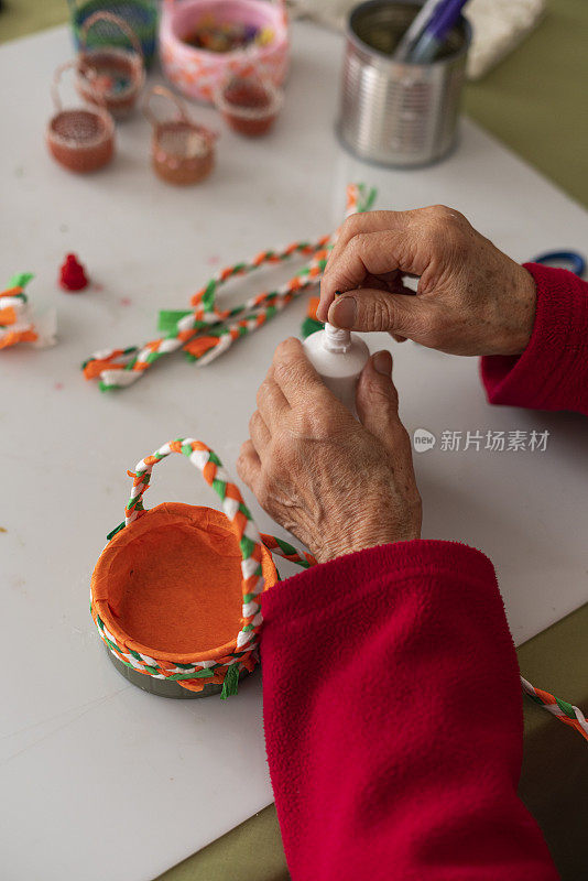 一位老妇人的手正在用材料制作工艺品