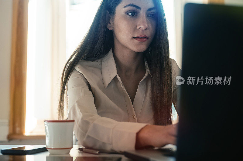 快乐微笑的女商人在她的办公桌上工作和喝咖啡的肖像