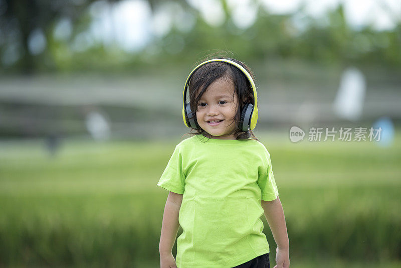 蹒跚学步的男孩用耳机听音乐