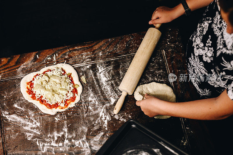 一家人在家里一起在厨房的桌子上做披萨，双手举在上面