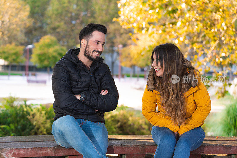 初次约会的年轻人坐在公园的木凳上谈笑风生