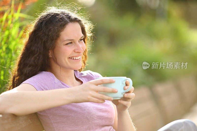 快乐的女人在公园里微笑着喝咖啡