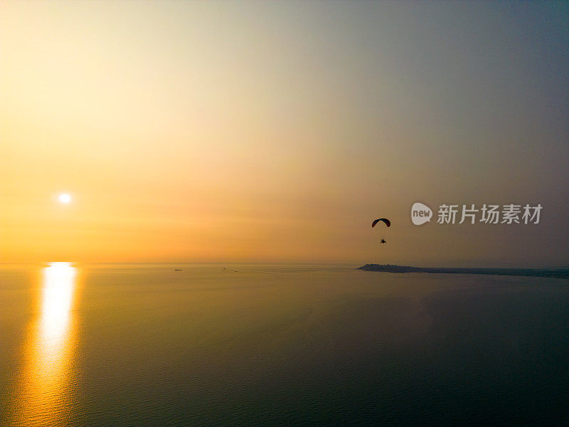 日落时的动力滑翔伞，俯瞰海洋