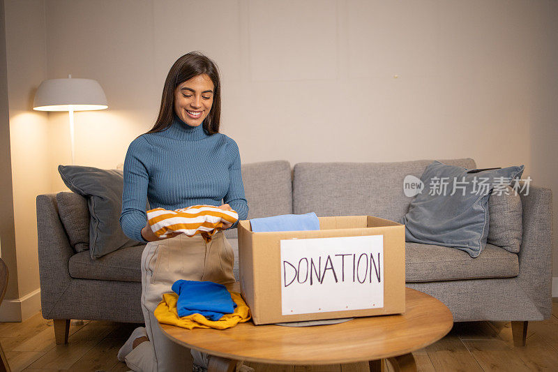年轻女子在整理衣物和打包捐款箱