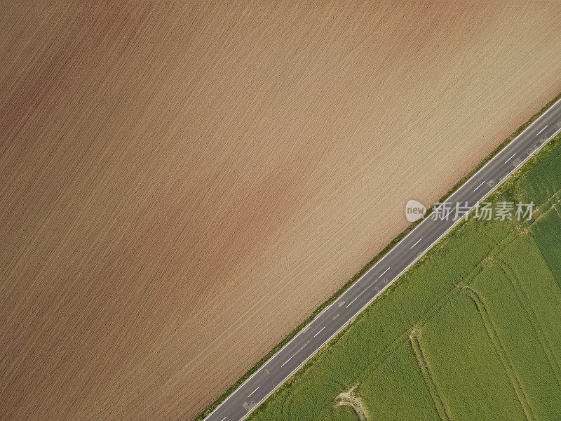 鸟瞰图:翻耕过的耕地、沥青路面和绿色的农田