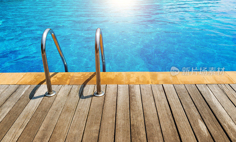 游泳池配有不锈钢梯子楼梯和木制甲板