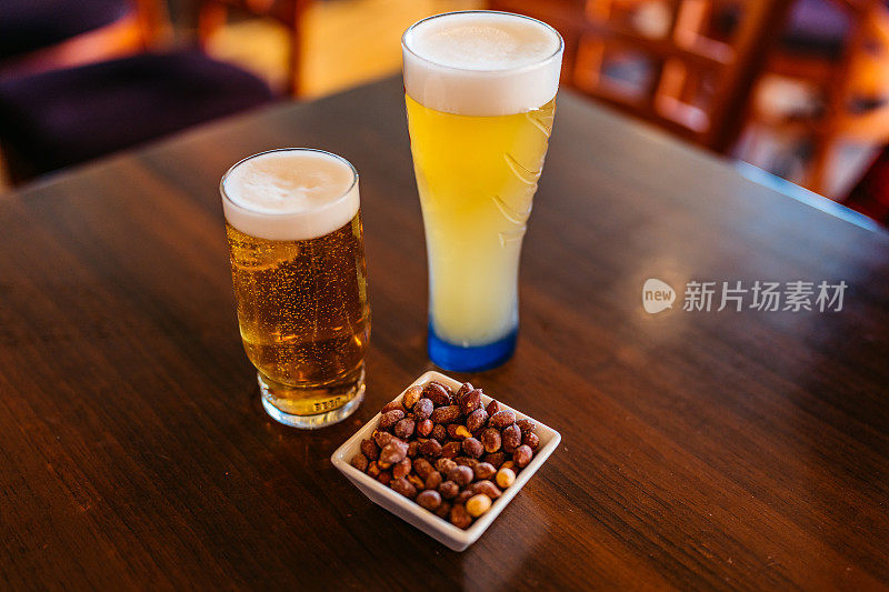 在酒吧的桌子上轻敲啤酒和花生