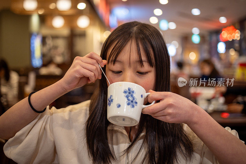 一个十几岁的女孩在餐厅吃完午饭后喝着一杯茶