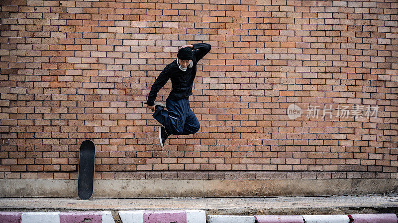 一个很酷、很有活力的亚洲男人在户外跳霹雳舞，在街上练习。
