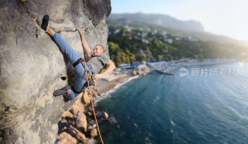 男性攀登者用绳子在大自然中攀爬巨石