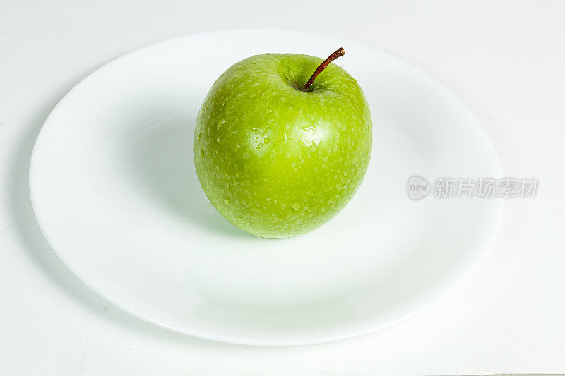 在盘子里有水滴的青苹果