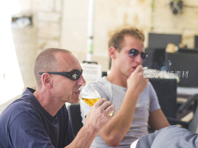 两名男子，在克罗地亚的Komiza餐厅抽烟喝酒
