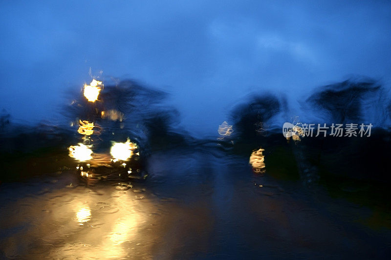 黄昏时分在大雨中行驶的汽车大灯在夜晚