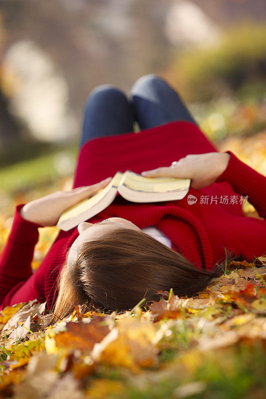 一个年轻的女人在读书，享受秋天