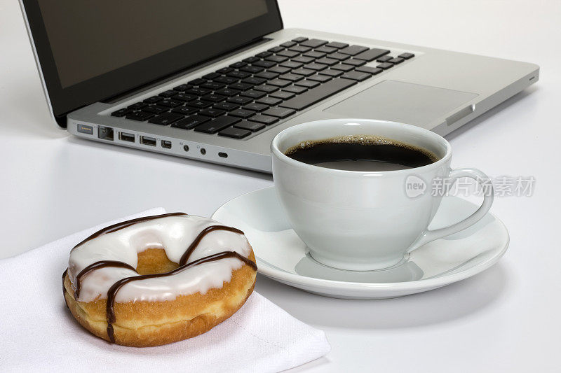 咖啡和甜甜圈放在笔记本电脑旁边