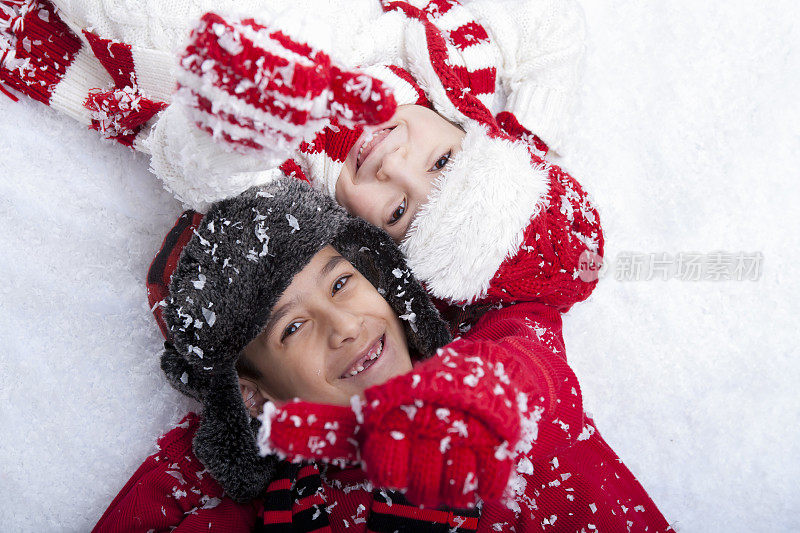 小男孩和小女孩躺在雪地里